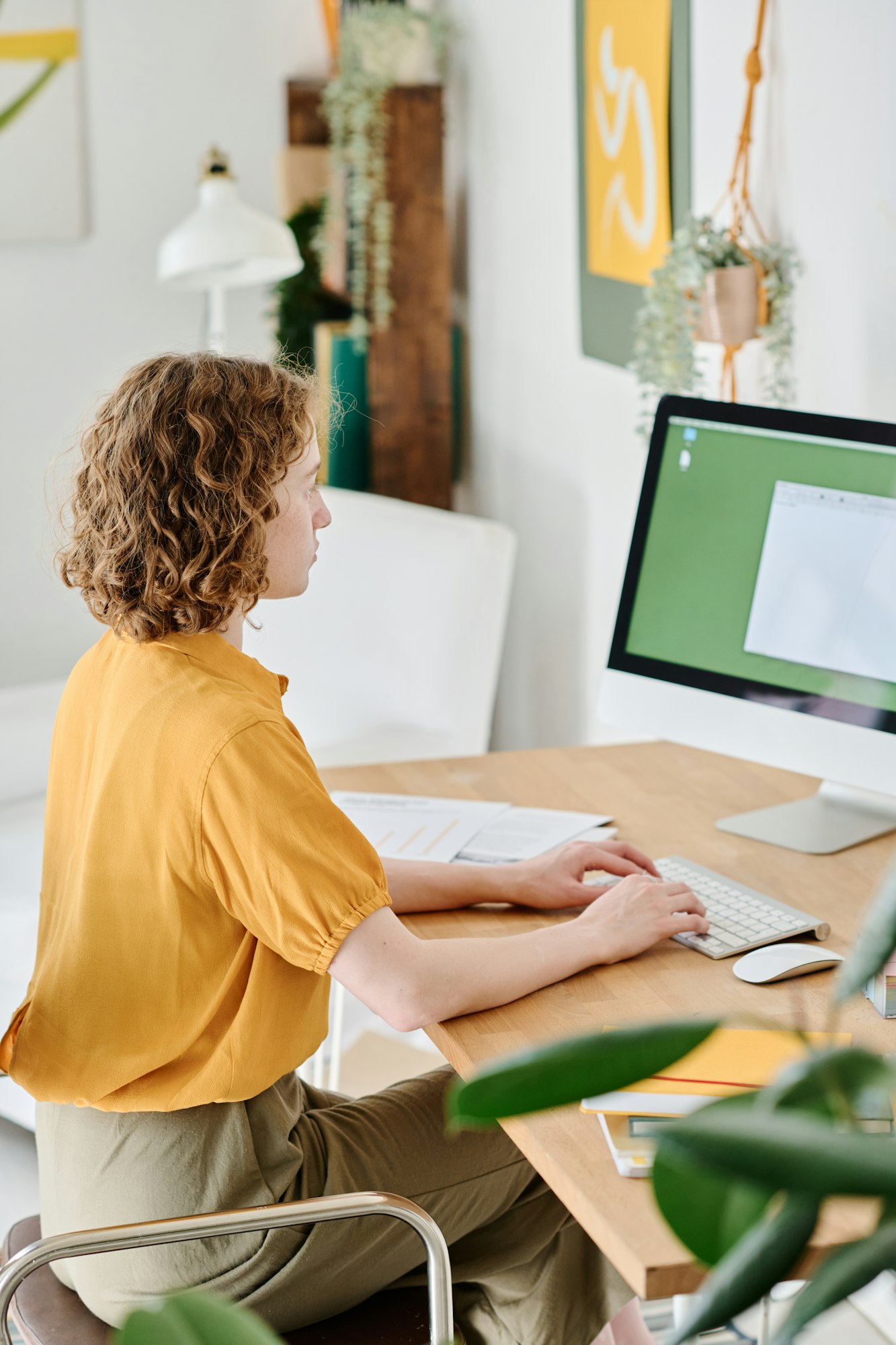 Young freelance webdesigner in casualwear with her hands over keyboard